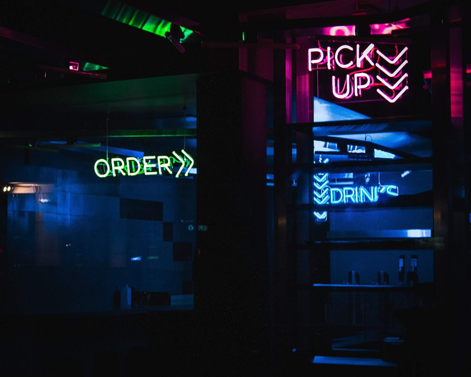 Neon Order and Pick Up signs in a modern restaurant, illustrating omnichannel ordering and pickup workflows powered by AI.