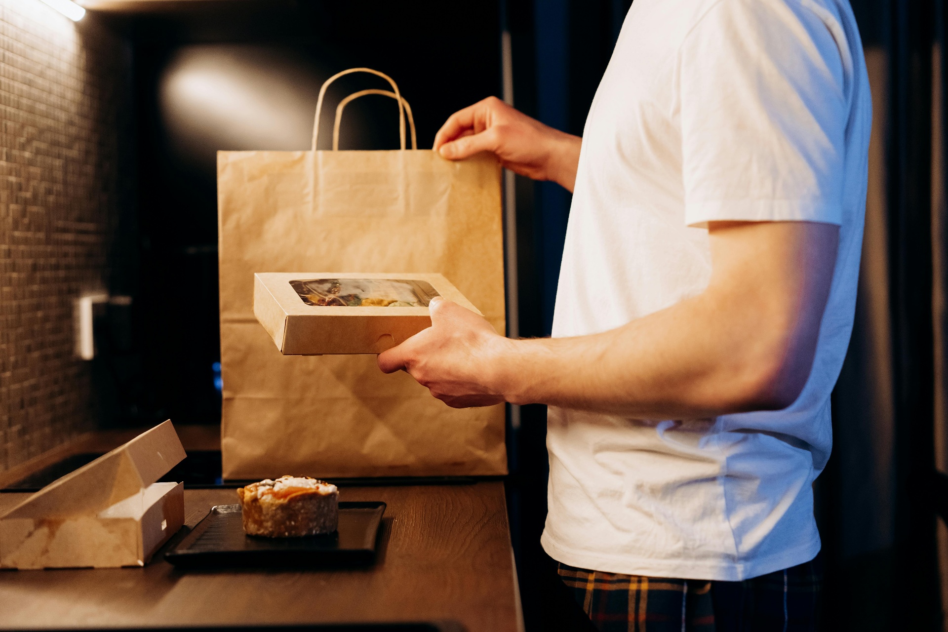 Restaurant staff handing a packaged takeout order in a paper bag, representing AI-powered direct ordering and pickup fulfillment.